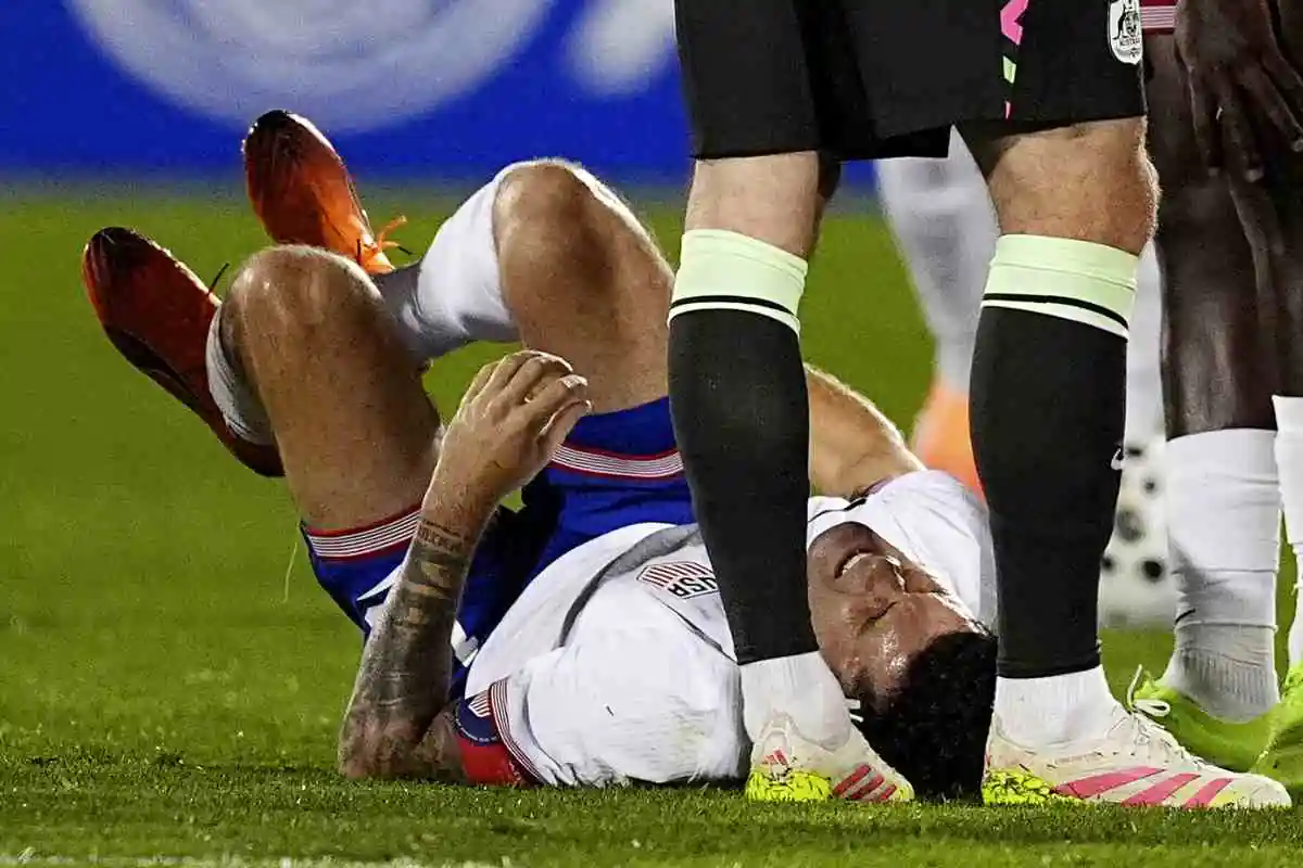 Christian Pulisic seduto a terra dopo un infortunio con la Nazionale degli Stati Uniti durante una partita del 2025