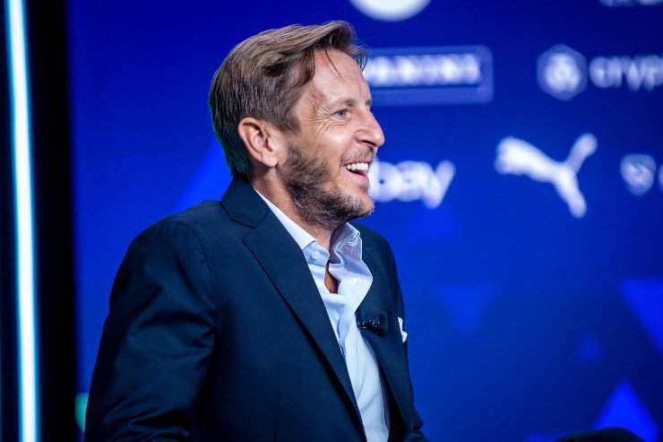 Massimo Ambrosini sorride durante il sorteggio del calendario di Serie A, seduto sul palco dell’evento ufficiale.