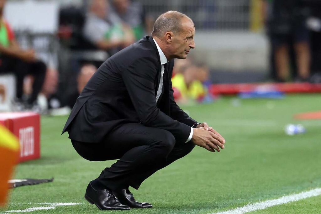 Max Allegri accovacciato nella sua area tecnica durante una partita del Milan