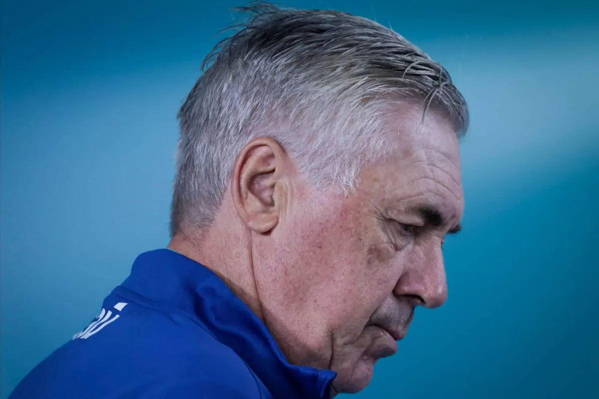 Carlo Ancelotti in primo piano durante un impegno stampa del 2024, con lo sguardo rivolto verso il basso.