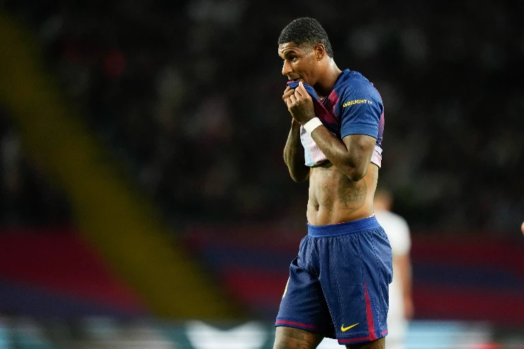 Marcus Rashford in maglia blu durante una partita, con mani al volto in gesto di concentrazione