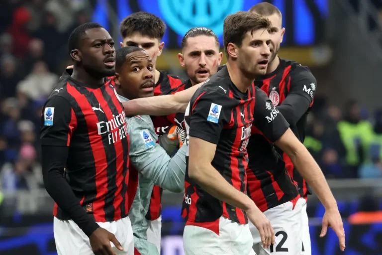 Giocatori del Milan abbracciano Maignan dopo una parata durante la partita