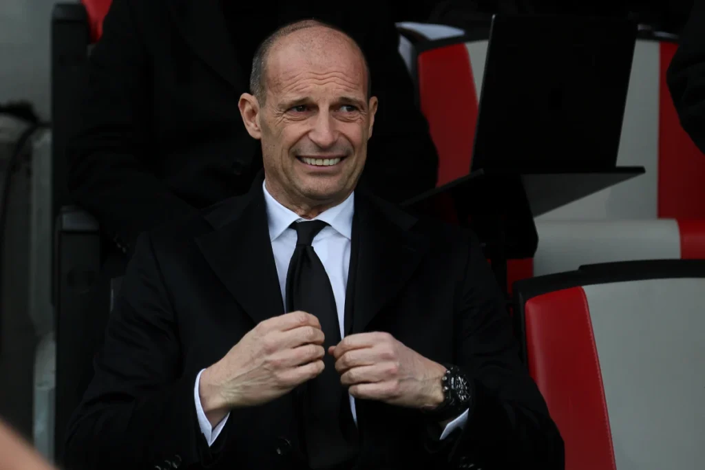 Massimiliano Allegri in abito scuro e cravatta nera in panchina durante una partita del Milan