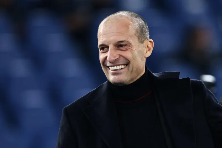 Massimiliano Allegri sorride durante un evento calcistico, indossando un cappotto nero