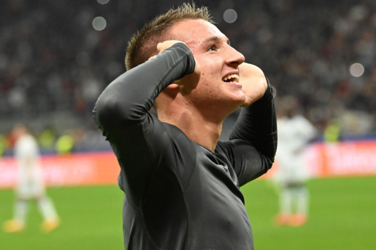 Francesco Camarda esulta con le mani alle orecchie durante una partita del Milan, rivolto verso il pubblico dello stadio