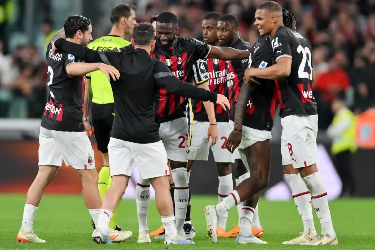 Giocatori del Milan in cerchio durante una partita, che si abbracciano e celebrano insieme in campo