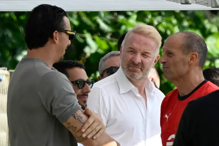 Igli Tare in discussione con dirigenti Milan durante un evento estivo, con Ibrahimovic e Allegri sullo sfondo