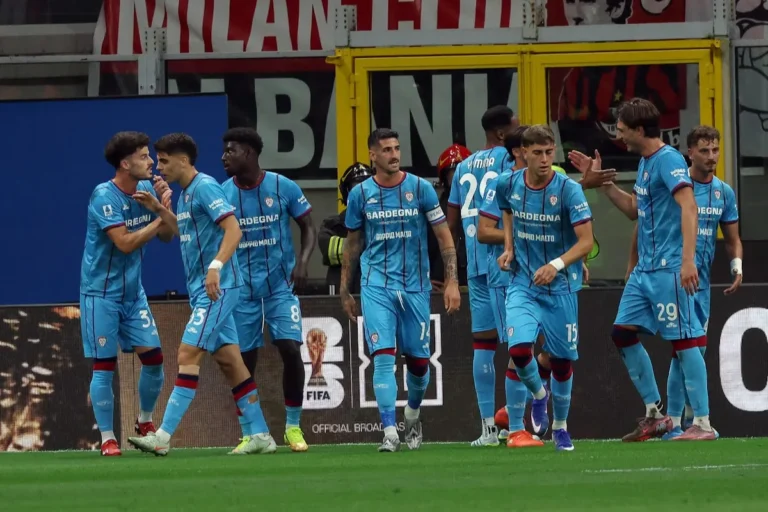 Giocatori del Cagliari in maglia azzurra durante la partita contro il Milan, con celebrazione in panchina