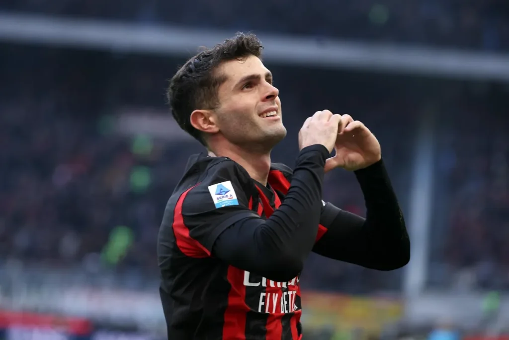 Pulisic in maglia Milan esulta durante una partita, mano sul cuore in gesto di dedizione