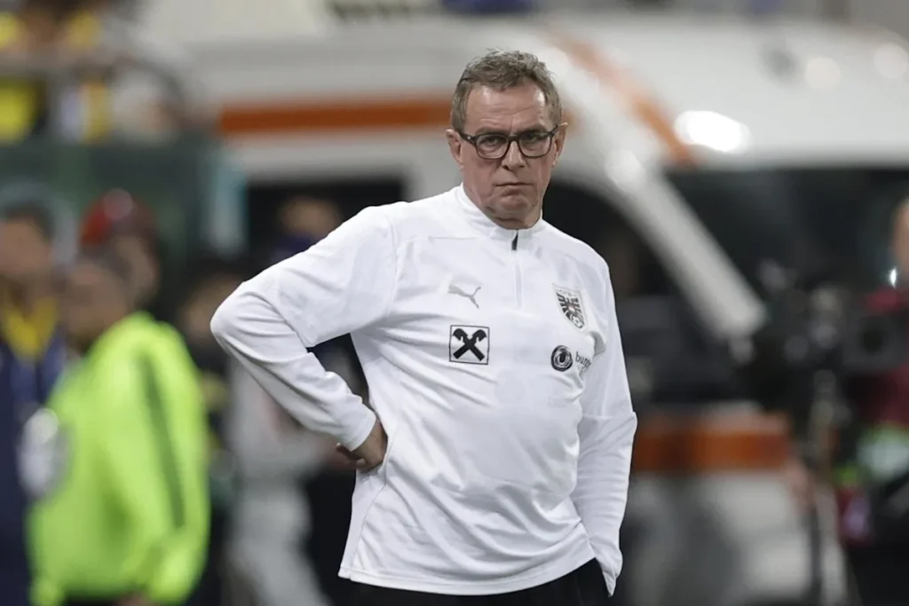 Ralf Rangnick in tuta tecnica bianca Puma in panchina durante una partita, con le mani sui fianchi