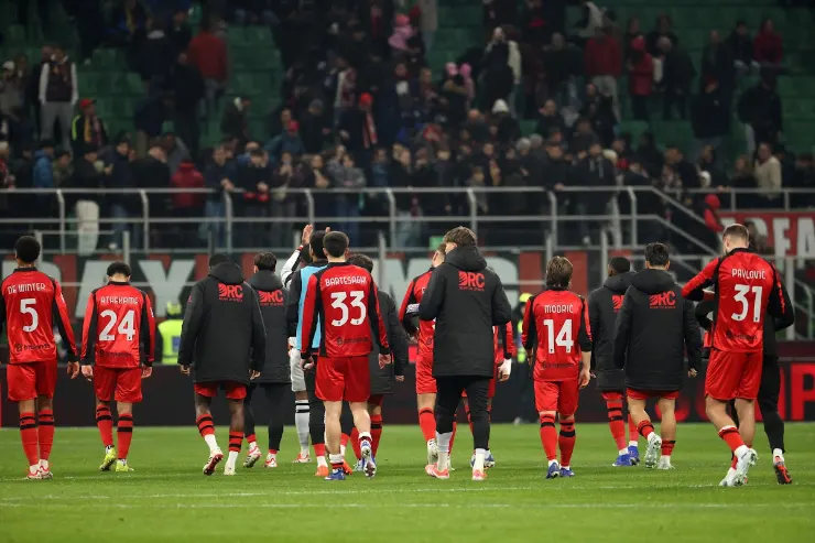 Giocatori del Milan con staff tecnico camminano sul campo, volti seri e delusi dopo la partita