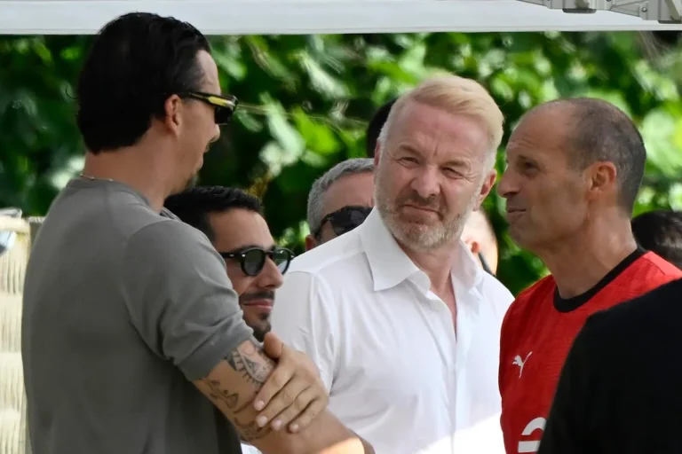 Igli Tare in discussione con dirigenti Milan all'aperto, tra cui Ibrahimovic e Allegri durante una riunione estiva