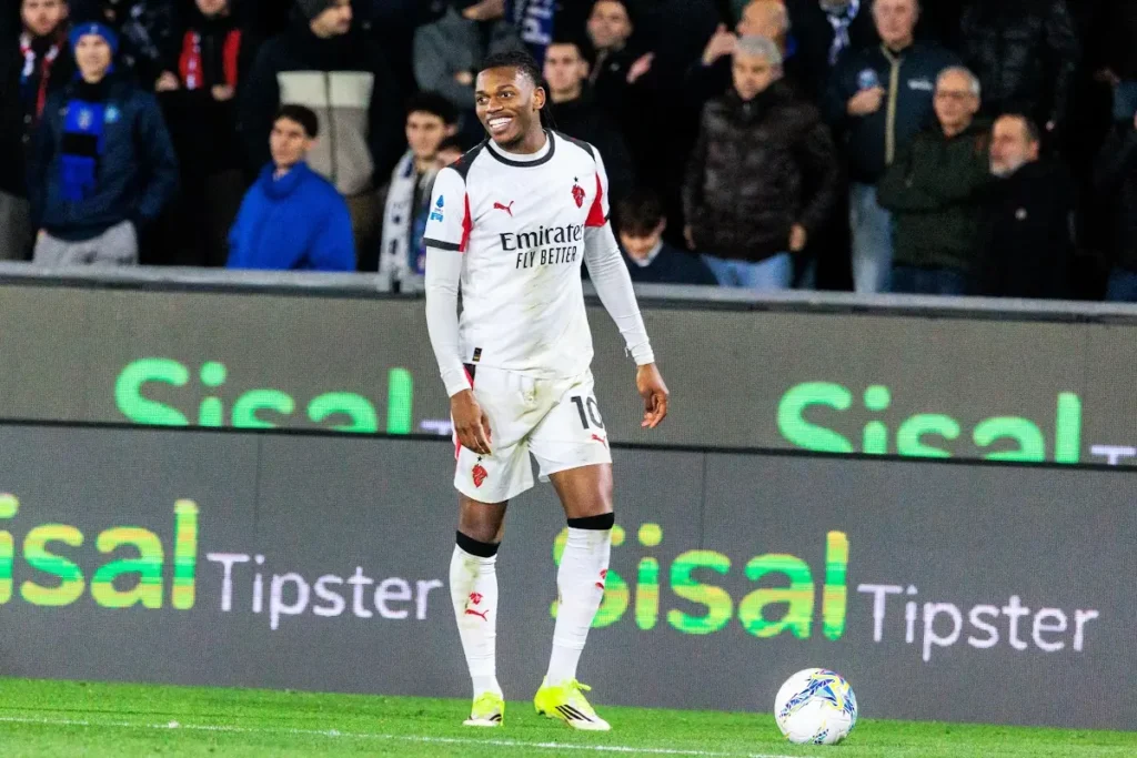 Rafa Leao in maglia bianca Arsenal numero 10 sorride in campo con pallone ai piedi