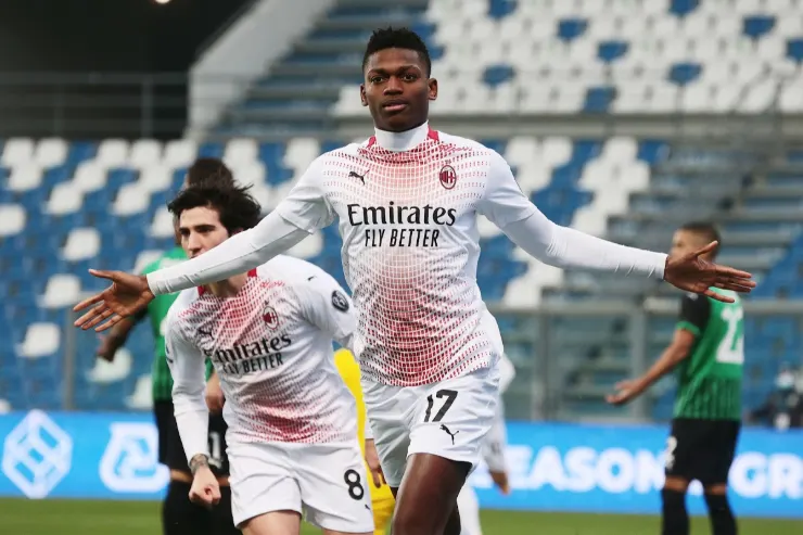 Rafael Leao con le braccia aperte durante una partita del Milan, indossa la maglia bianca con sponsor Emirates