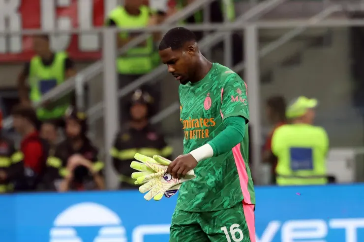 Mike Maignan portiere del Milan in maglia verde durante una partita, con lo sguardo rivolto verso il basso