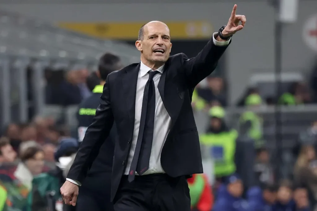 Max Allegri impartisce indicazioni dalla panchina durante una partita, in abito formale