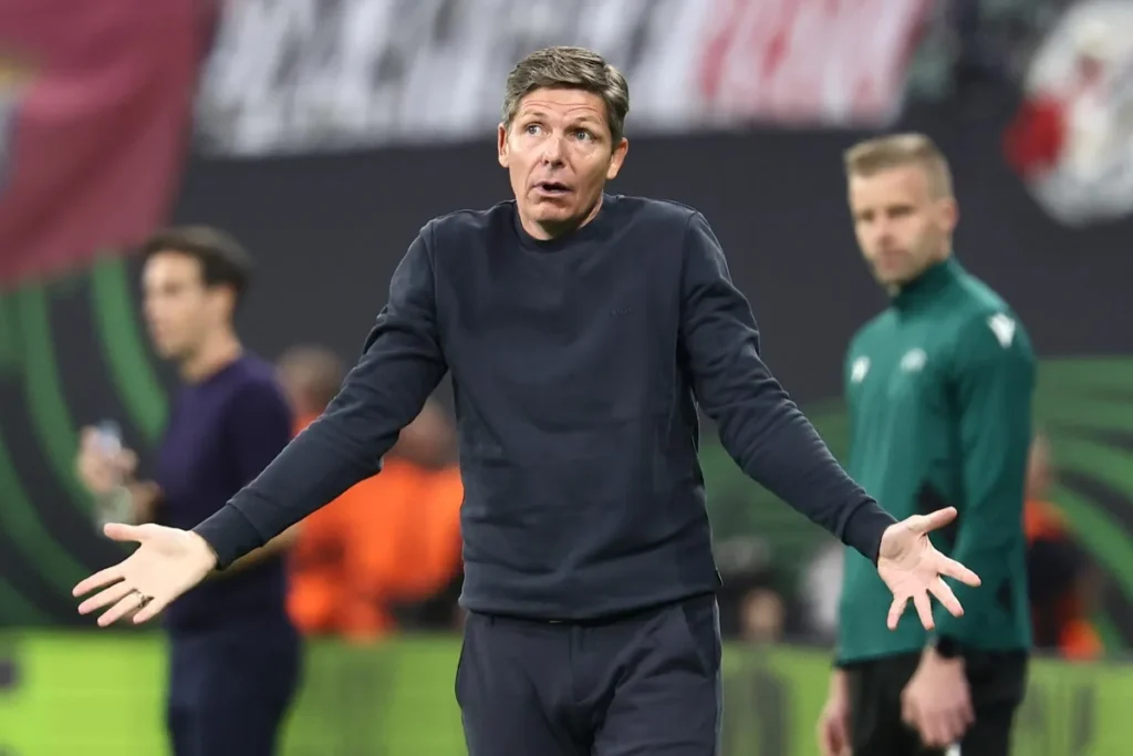 Oliver Glasner in panchina con gesto espressivo durante una partita, braccia aperte mentre dirige la squadra