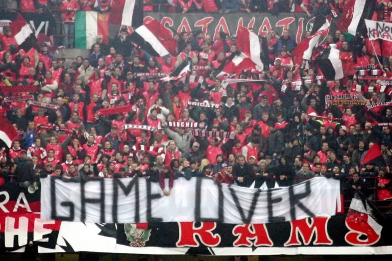 Curva Sud del Milan durante una partita, tifosi rossoneri con bandiere italiane e striscioni, tribuna gremita