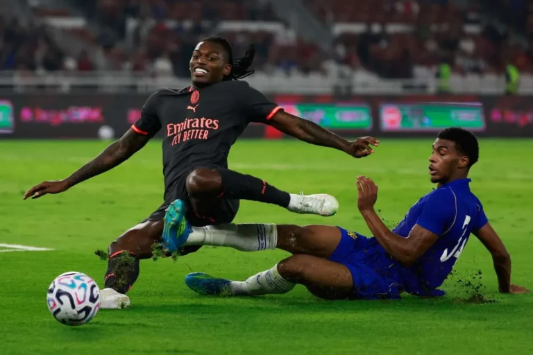 Leao in maglia nera contrasta un avversario del Chelsea in maglia blu durante un'amichevole