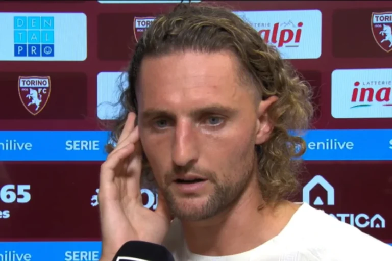 Adrien Rabiot durante un'intervista, con microfono in primo piano e sfondo sponsor Torino