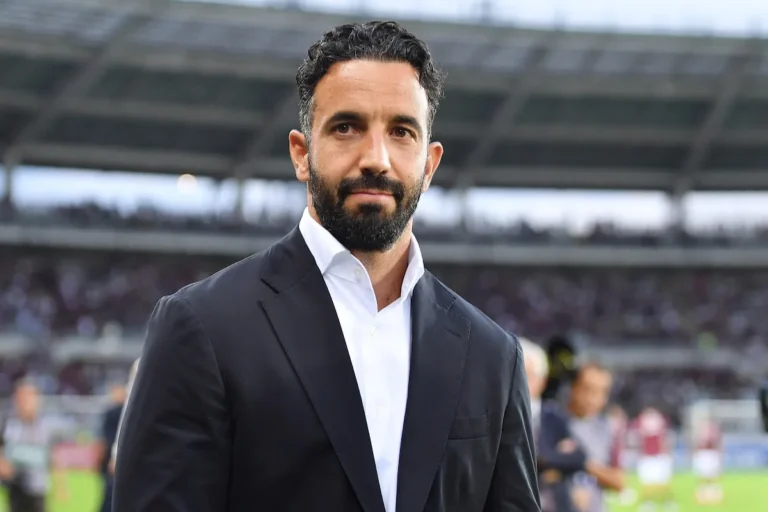 Ruben Amorim in giacca nera e camicia bianca nello stadio del Milan, ritratto dalla tribuna durante la partita