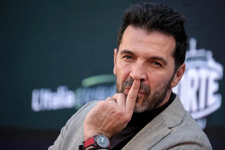 Gianluigi Buffon in giacca grigia a una conferenza stampa, con espressione concentrata