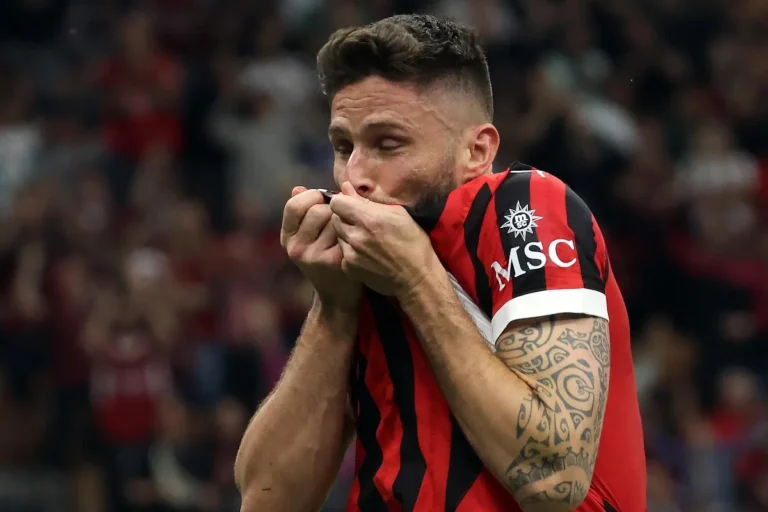 Giroud bacia la maglia del Milan durante una partita, indossando la divisa rossonera con sponsor MSC