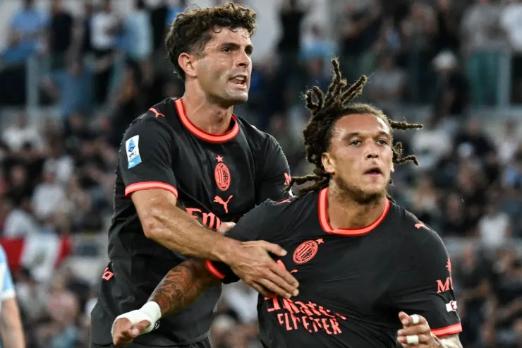 Pulisic e Moreira in azione durante la partita del Milan, con lo stadio sullo sfondo