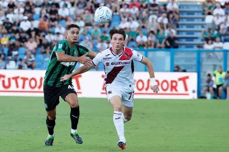 Partita Sassuolo-Torino in Serie A, giocatore del Sassuolo in maglia verde-nera contrastata del Torino in maglia bianca con sponsor Suzuki