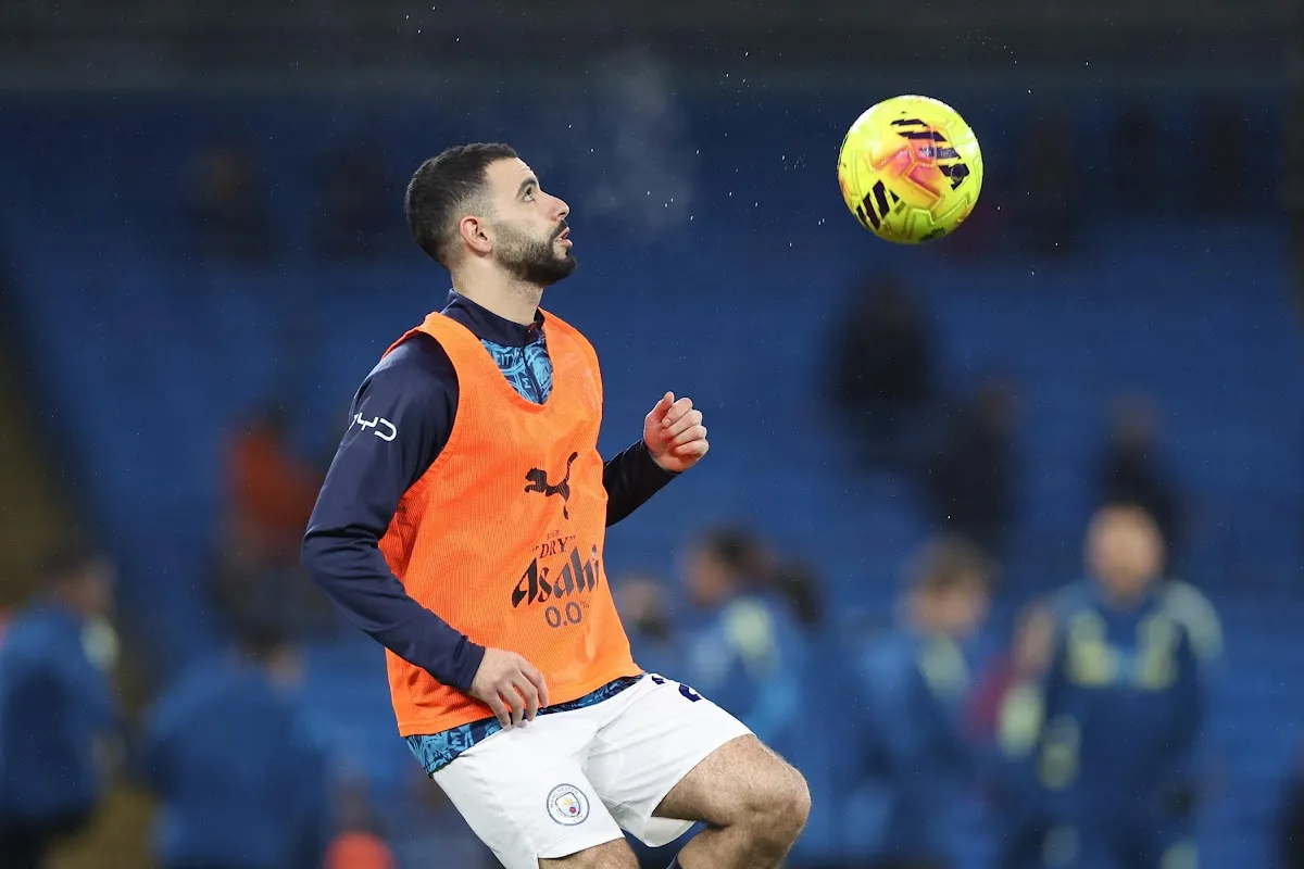 Aït-Nouri durante l'allenamento con il Manchester City indossa il giubbetto arancione e osserva il pallone