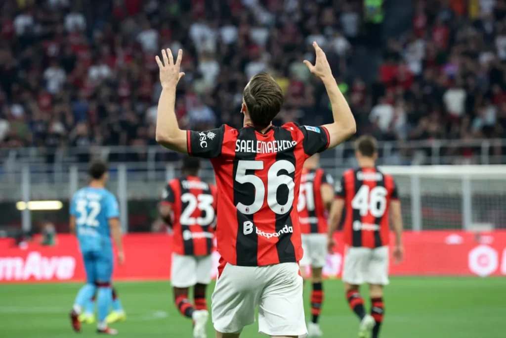 Alexis Saelemaekers di spalle con le braccia alzate, maglia rossonera numero 56, durante una partita del Milan