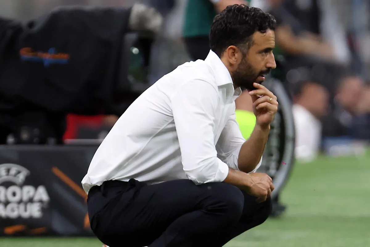 Amorim accovacciato a bordo campo con camicia bianca e mano sul mento, pannello UEFA Europa League alle spalle