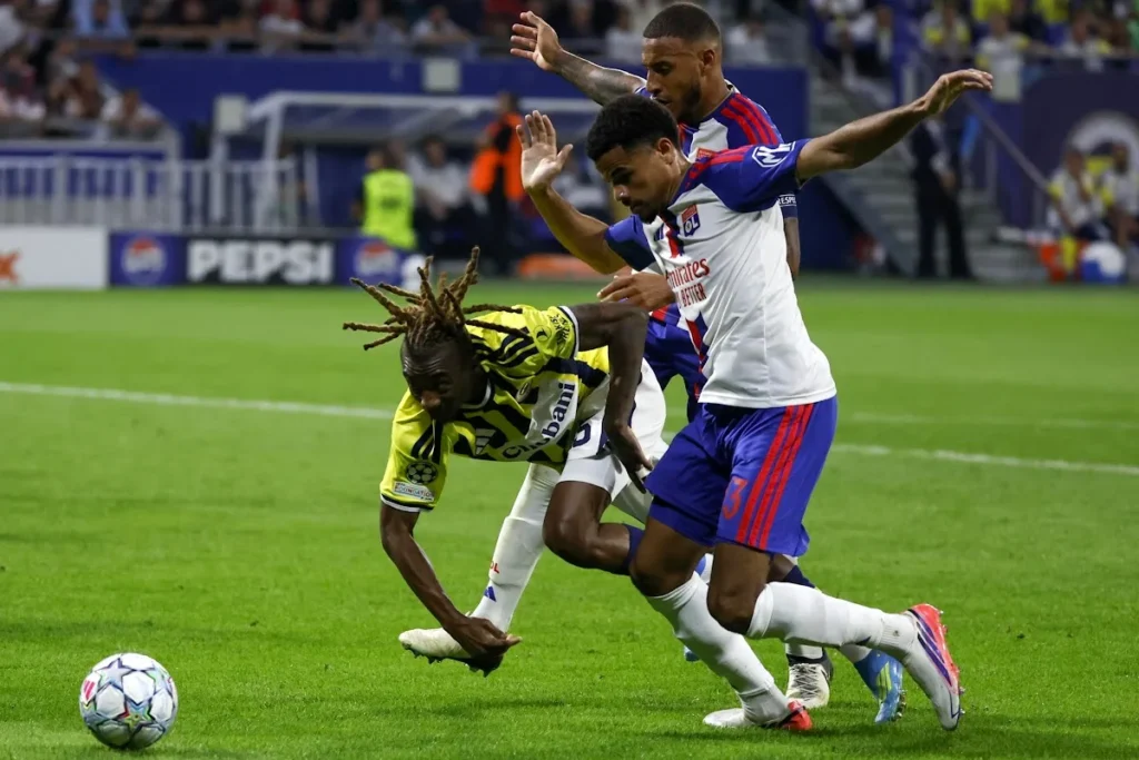Athekame del Lione con maglia bianca e blu numero 3 contrasta un avversario del Fenerbahce in Champions League