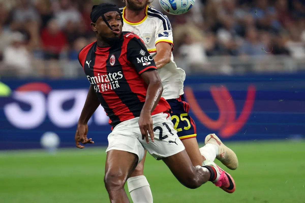 Chukwueze con la maglia rossonera a righe durante una partita del Milan, contrasto con un avversario in maglia bianca