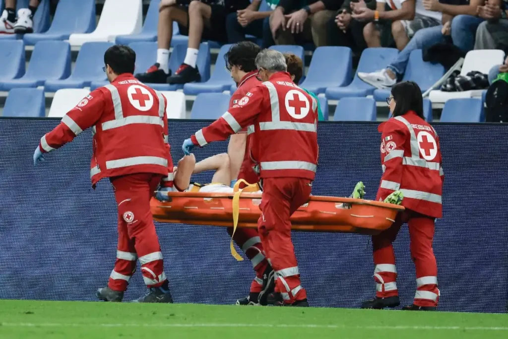 Gabbia in barella arancione portata via dai soccorritori sul prato dello stadio