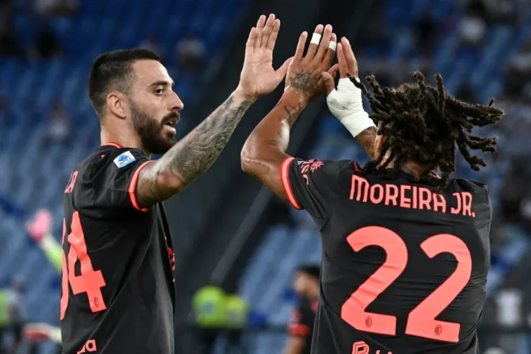 Due giocatori del Milan con maglia nera si danno il cinque durante una partita; a destra Moreira Jr., numero 22