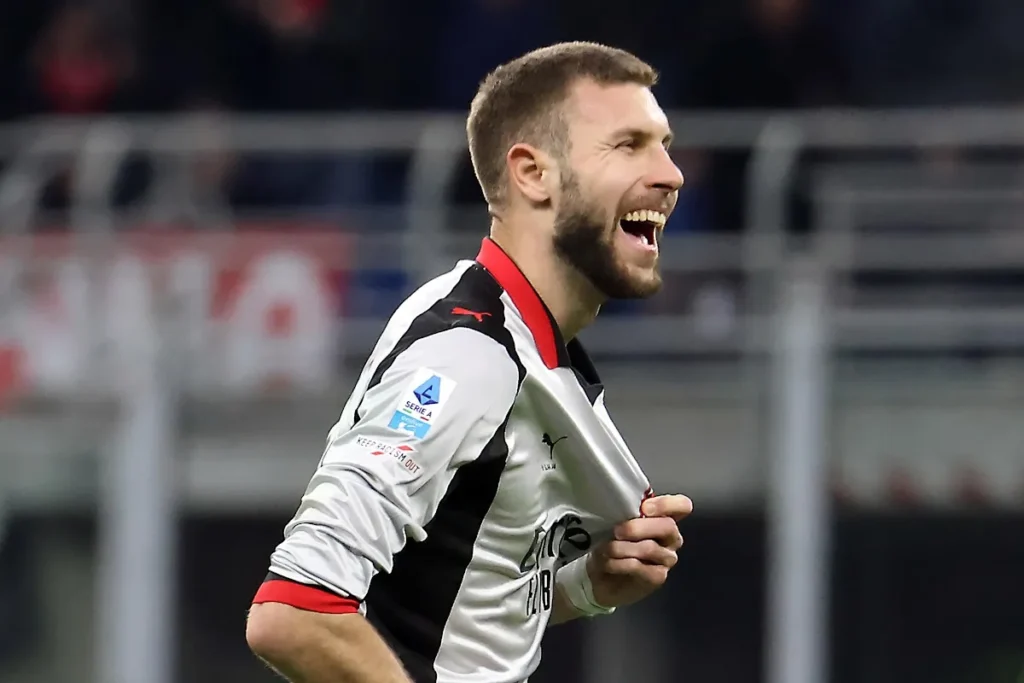 Giocatore del Milan con maglia bianca e nera Puma sorride durante una partita di Serie A