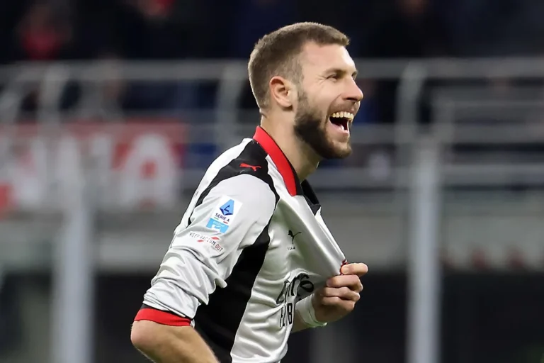 Giocatore del Milan con maglia bianca e nera Puma sorride durante una partita di Serie A