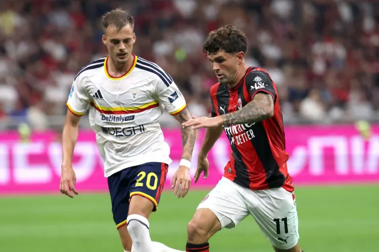 Pulisic in azione durante una partita del Milan, contrasta un avversario in maglia bianca