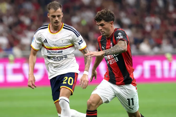 Pulisic in azione durante una partita del Milan, contrastato da un difensore avversario