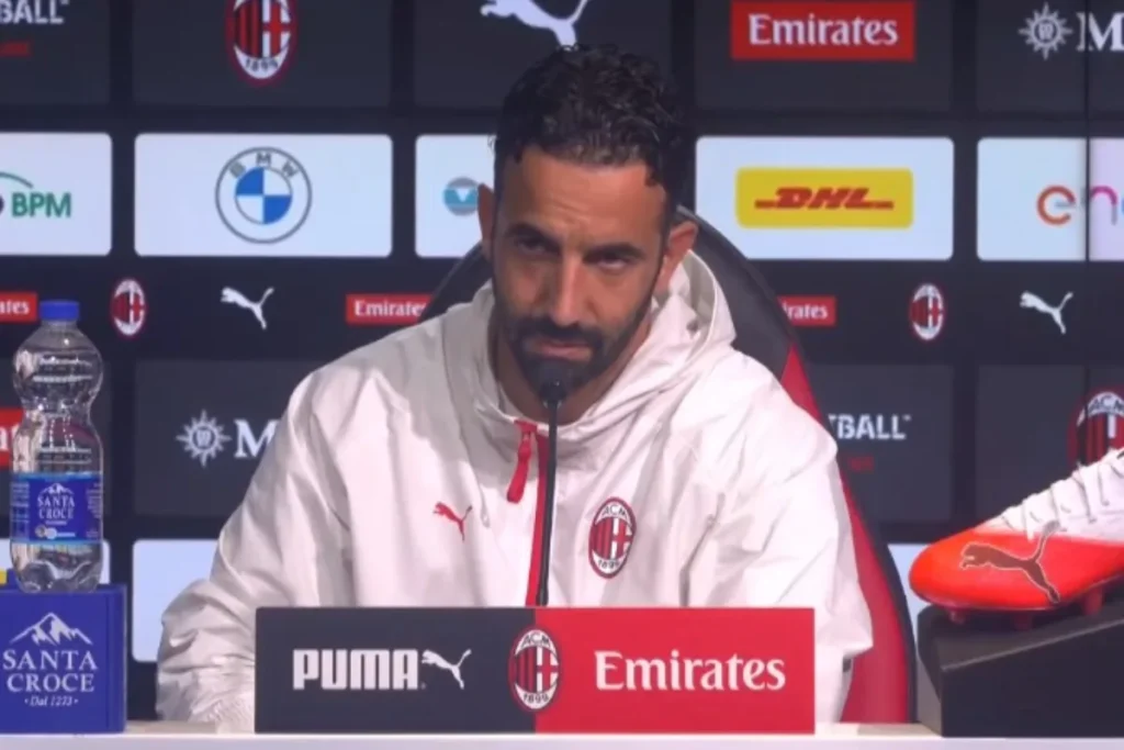 Amorim del Milan in conferenza stampa con microfono davanti al backdrop ufficiale con sponsor